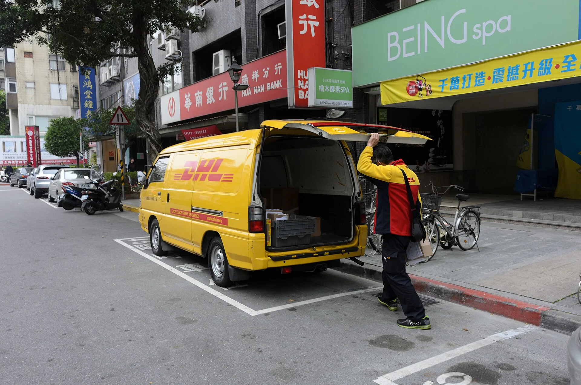 ​取出投遞物件後，關上三菱得利卡廂型車後門的洋基通運快遞員。攝於臺北市松山區民生東路五段，左前方為華南銀行瑞祥分行。. Delivery driver contractor or employee: the test that decides