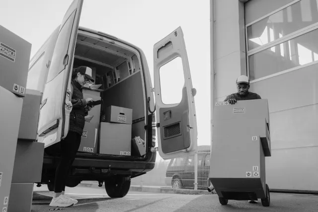 Delivery workers unloading packages from a van using a trolley at a distribution center. FMCSA rules for local courier fleets before the first route