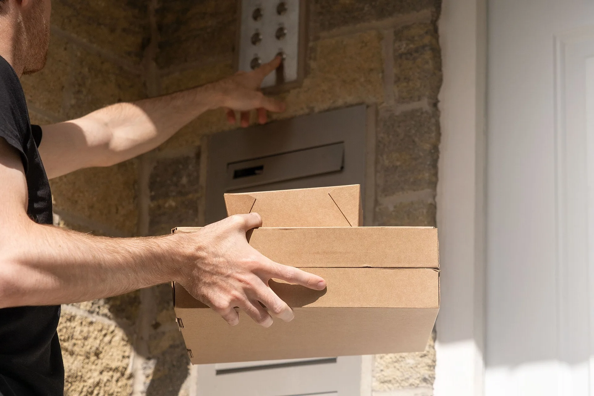 A photo of a delivery driver delivering two boxes of takeaway food to an apartment block. He's reaching up to ring the doorbell for one of the apartments while holding the boxes in his other hand. We took this photo to use on our website, but have decided to release it under Creative Commons instead. How a local delivery business keeps service quality honest for a small operation