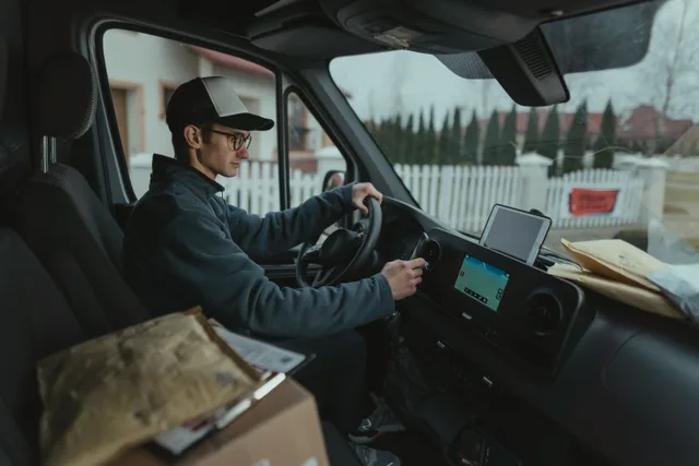 Courier driving van with packages, using GPS for efficient delivery route. Local delivery expansion: name the move, measure four weeks