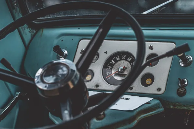Detailed view of a vintage vehicle's dashboard with speedometer and steering wheel. New vs used local delivery equipment: decision factors